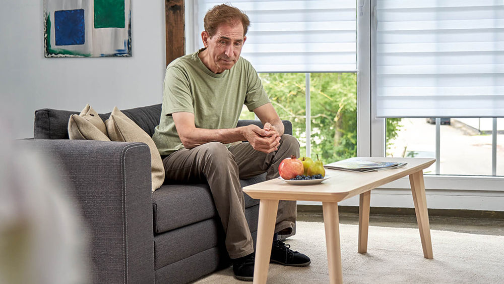 người đàn ông mỏng tuổi ngồi trên ghế sofa một cách chu đáo