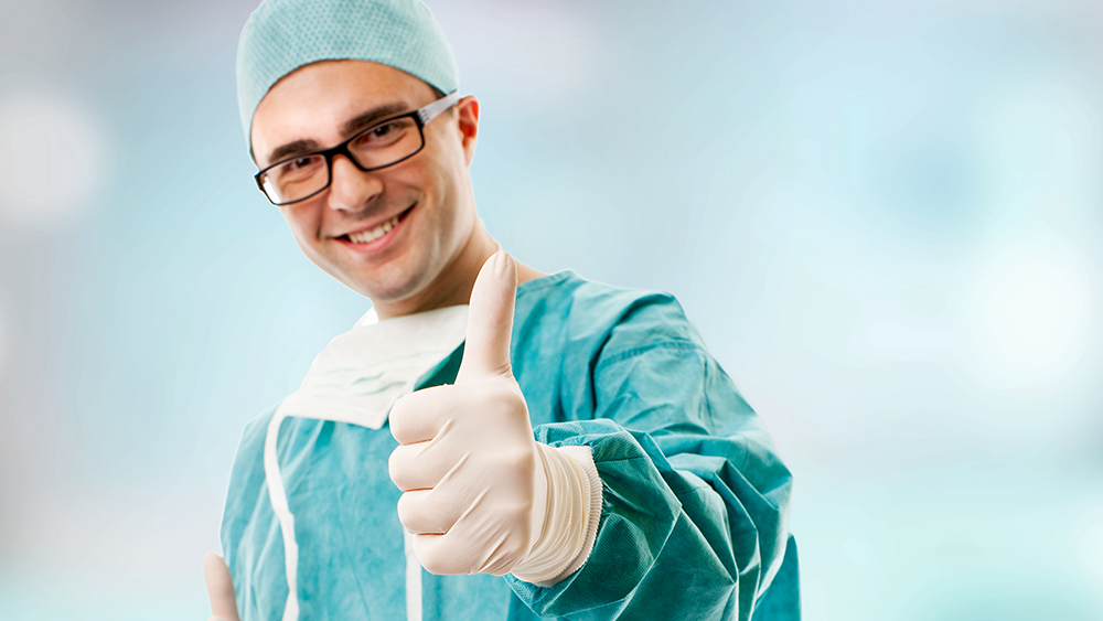 Bác sĩ phẫu thuật trẻ với giơ ngón tay thể hiện sự hài lòng