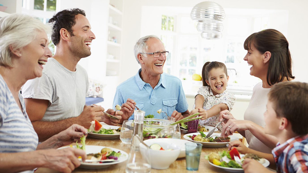 Một gia đình ngồi ở bàn ăn và cười