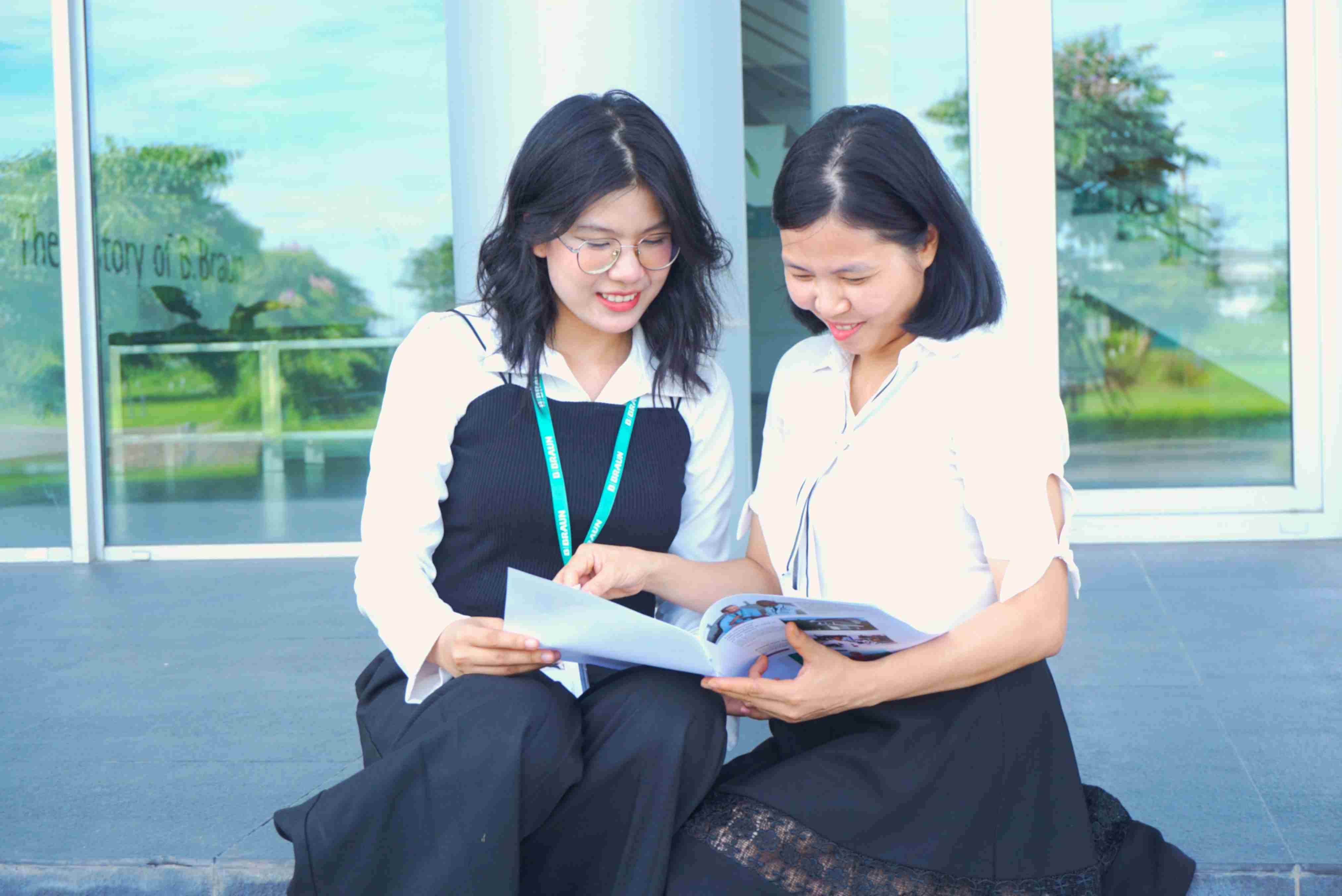 Hai người thảo luận về mô hình và biểu đồ kinh doanh trên máy tính trong phòng văn phòng. 