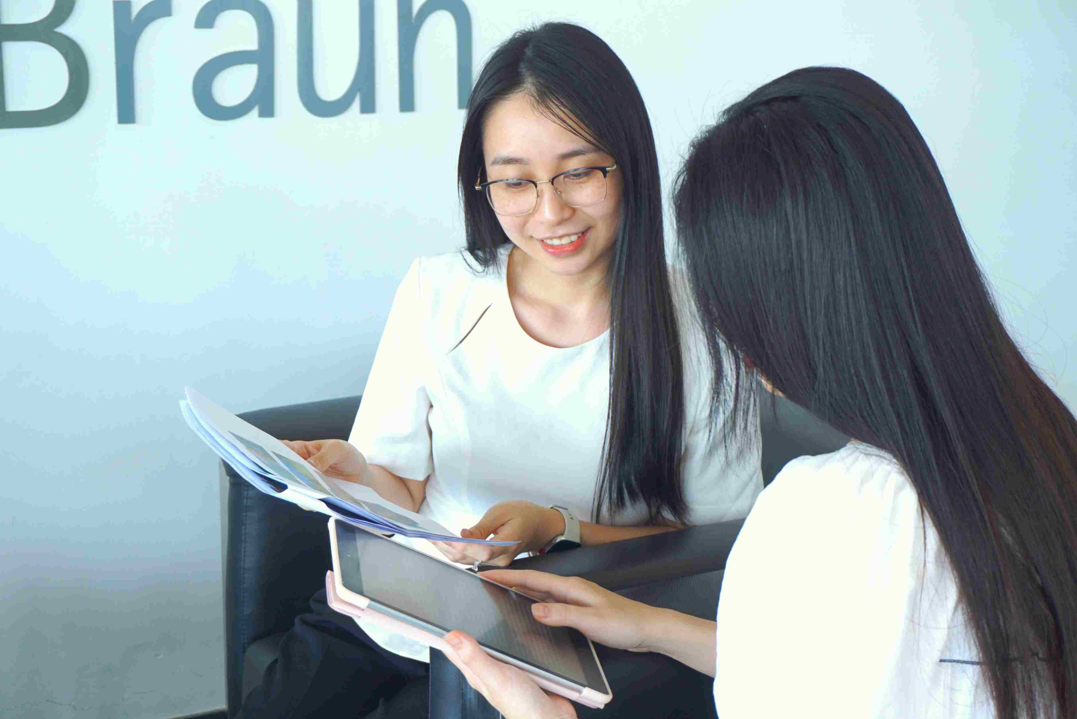 Hai người thảo luận về mô hình và biểu đồ kinh doanh trên máy tính trong phòng văn phòng. 