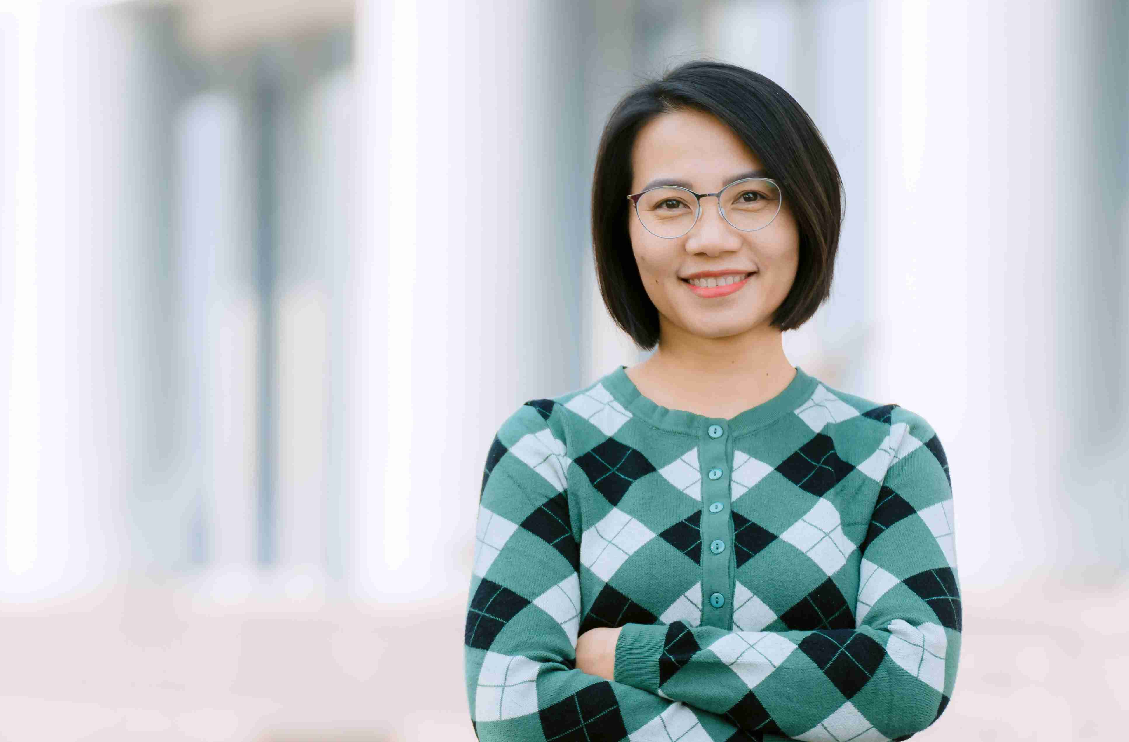 Một phụ nữ tự tin trong bộ suit màu xám nhìn nghiêng qua ống kính.  