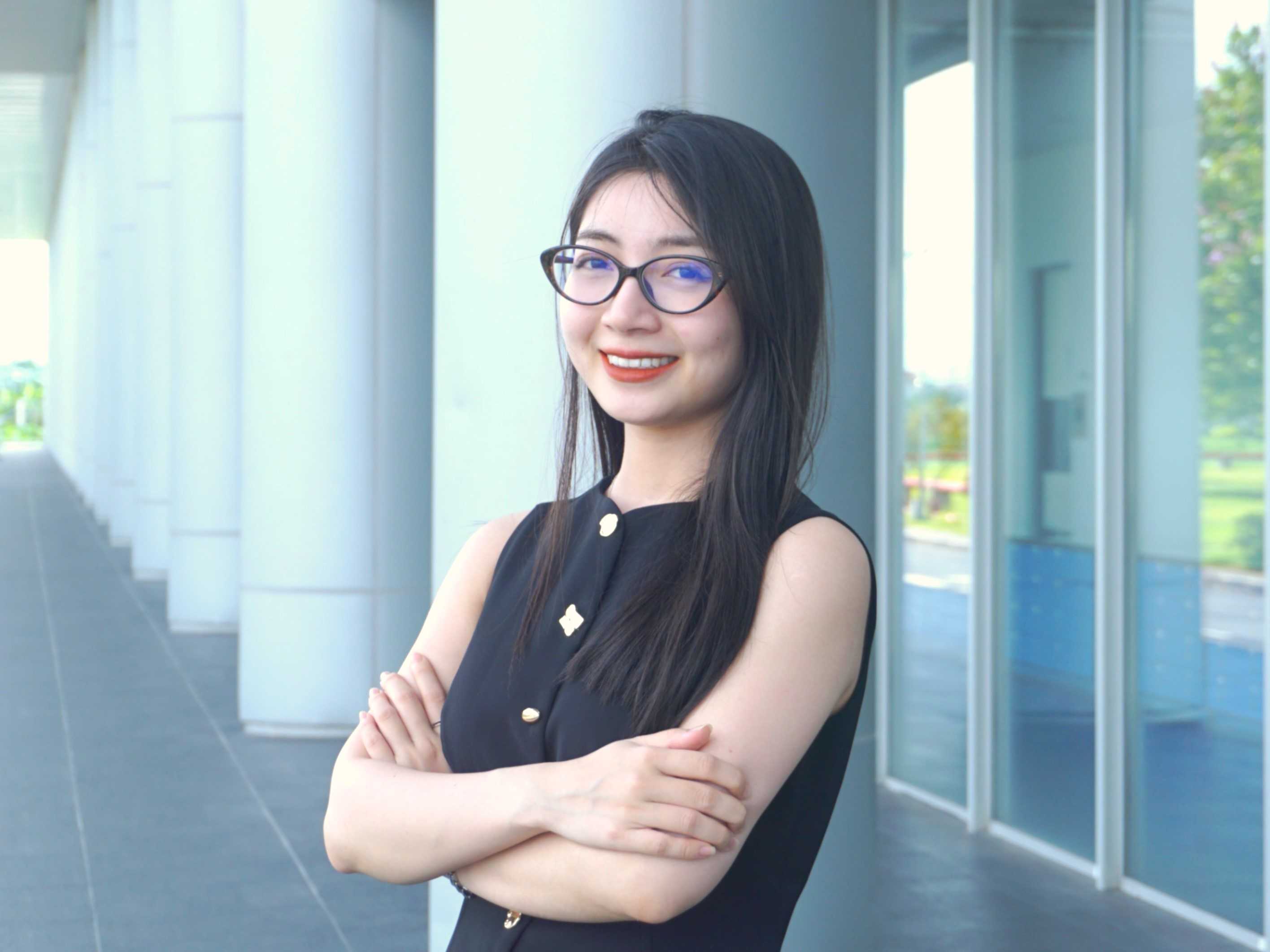 Cận cảnh một người phụ nữ đang nhìn vào máy ảnh, mỉm cười trong một khung cảnh tươi sáng. 